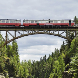 Ein Zug auf einer Brücke in einer bergigen Landschaft